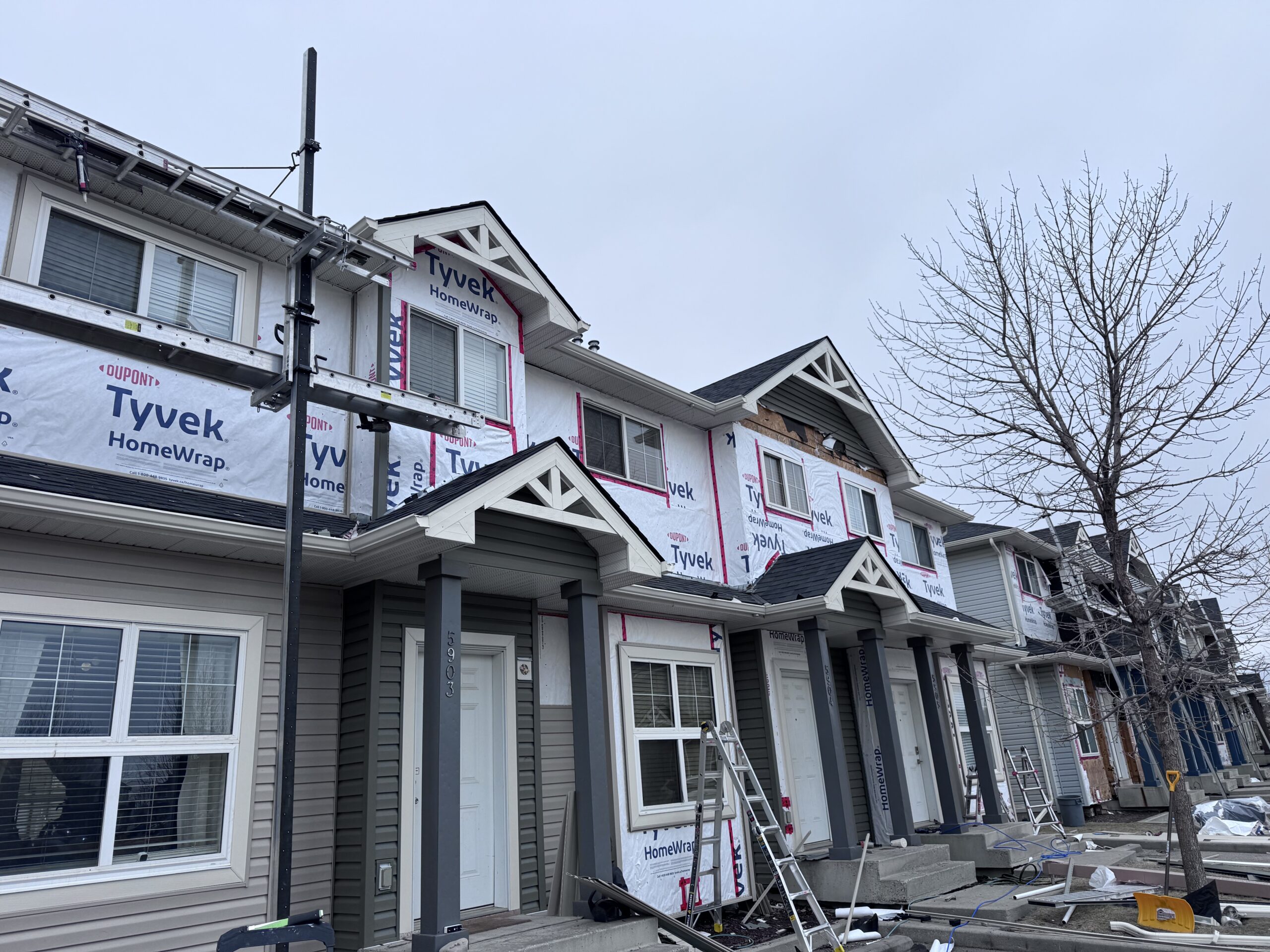 Gable ends in house wrap, staged with scaffolding before the vinyl siding goes on