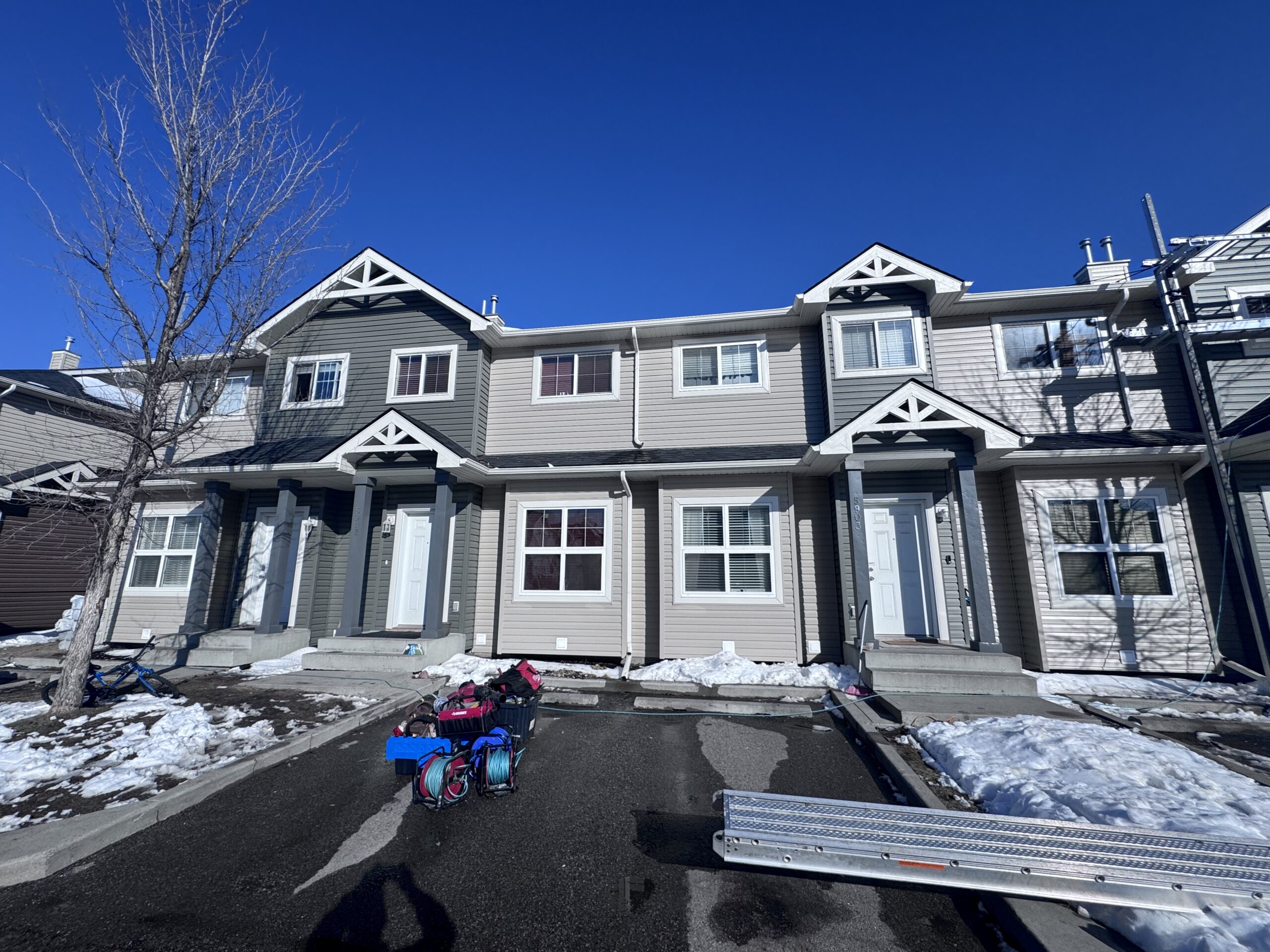 Finished vinyl siding on a townhome row with white gable trim under a clear blue sky