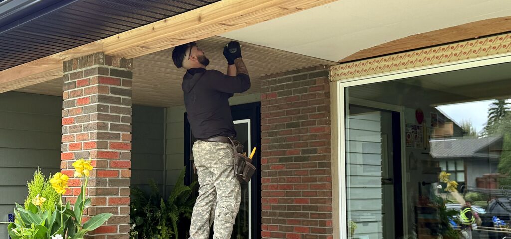 Installer fitting soffit under a covered porch ceiling