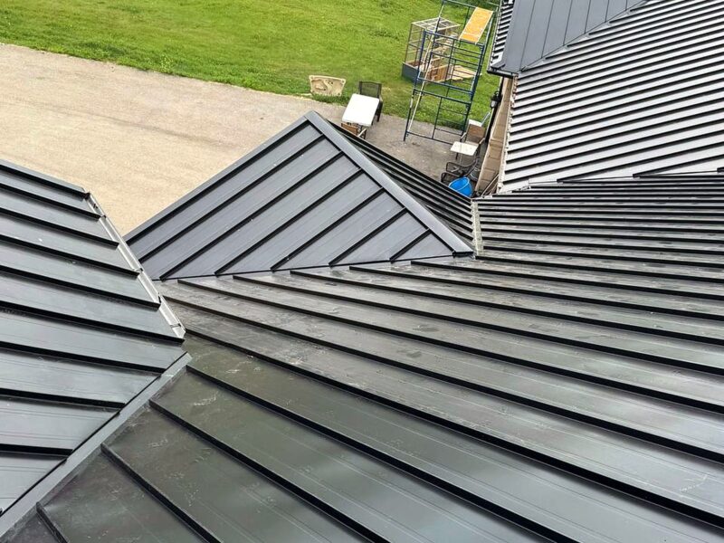 Black standing seam metal roof panels with an acreage yard beyond