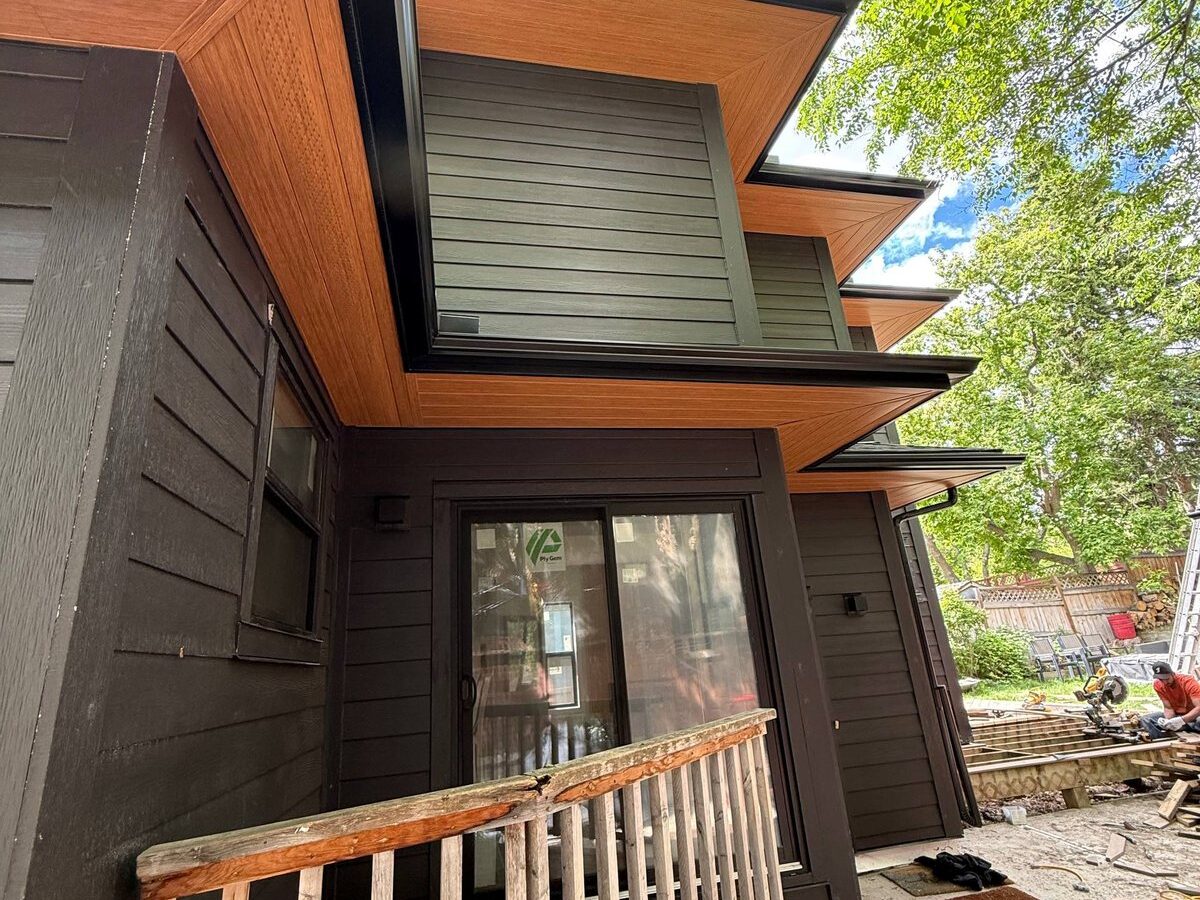 Cedar-look soffit under deep eaves on a dark fibre cement elevation