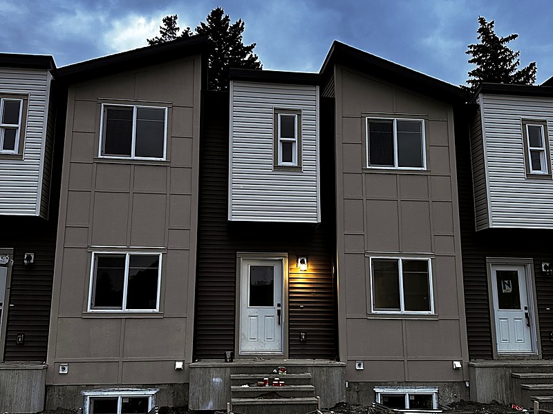 Dark siding with white vertical panel accents on a row of Calgary townhouses