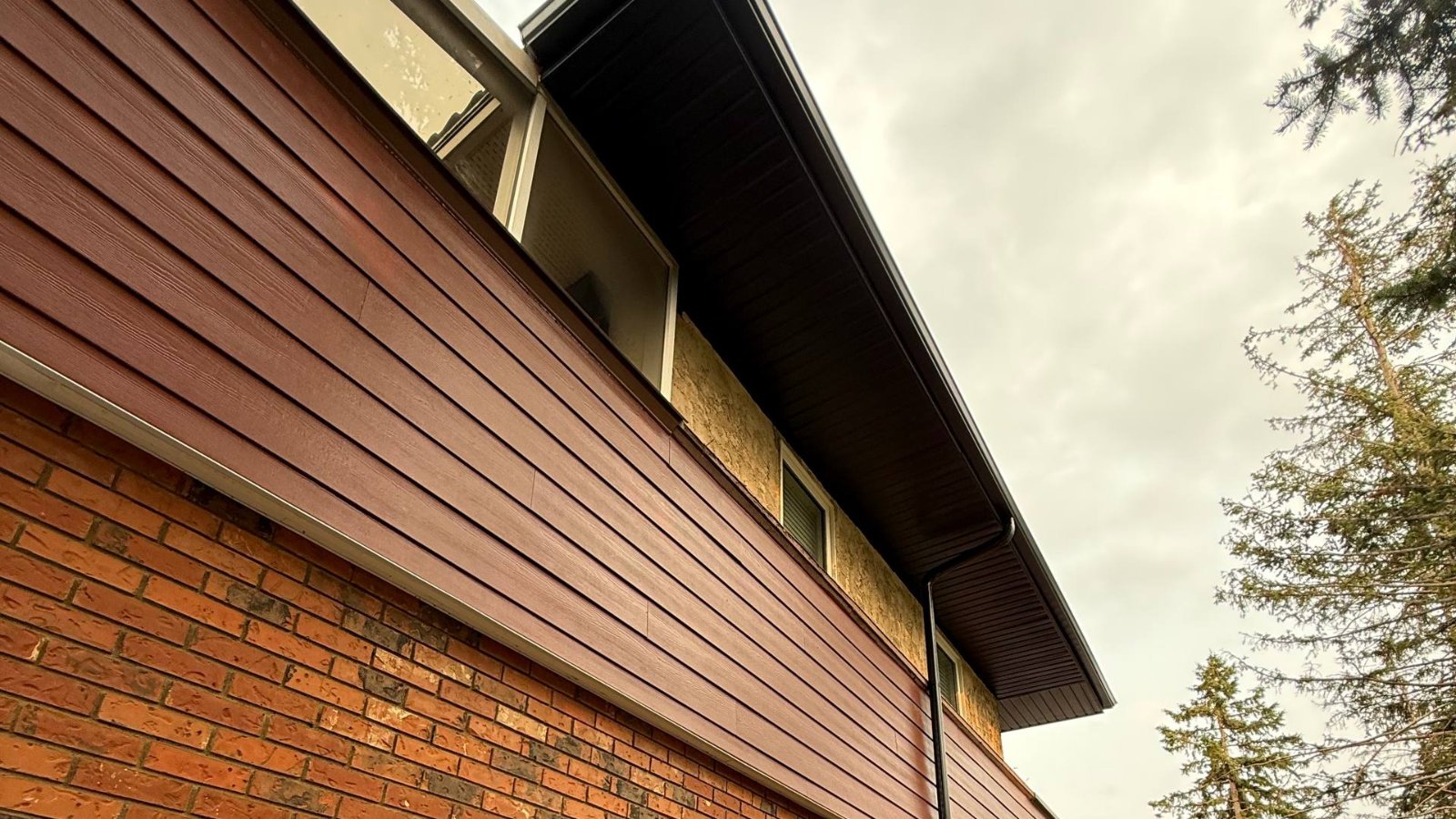 The line of the eave with fascia and soffit running above a brick wall
