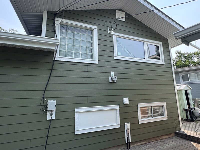 Green lap siding across a full side elevation with white window trim