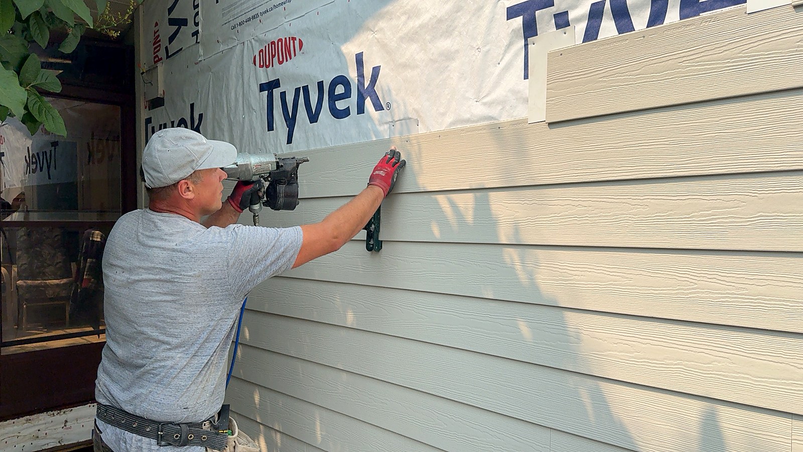 Installer fastening a lap board over a DuPont Tyvek weather barrier
