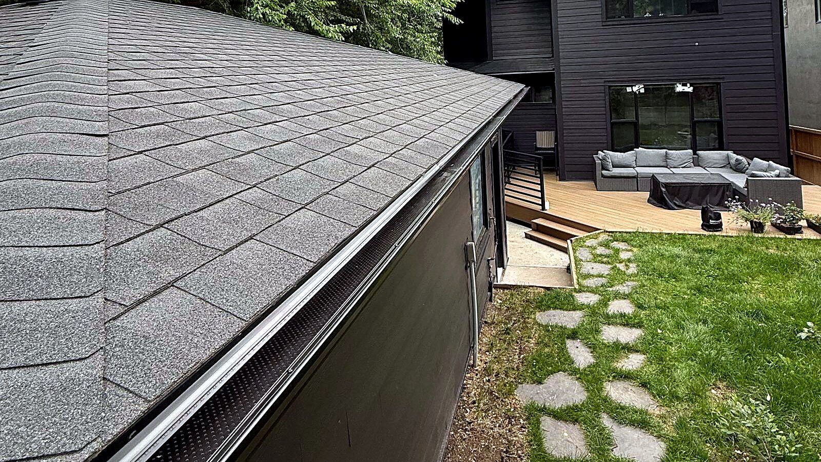 Perforated gutter guard running along the roof edge of a garage in a Calgary backyard