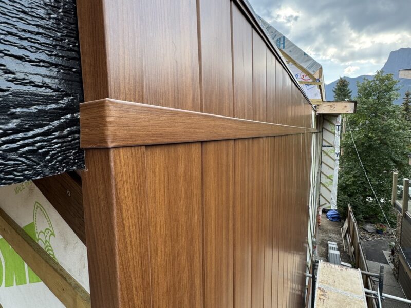 Wood-grain metal siding panels installed over weather barrier