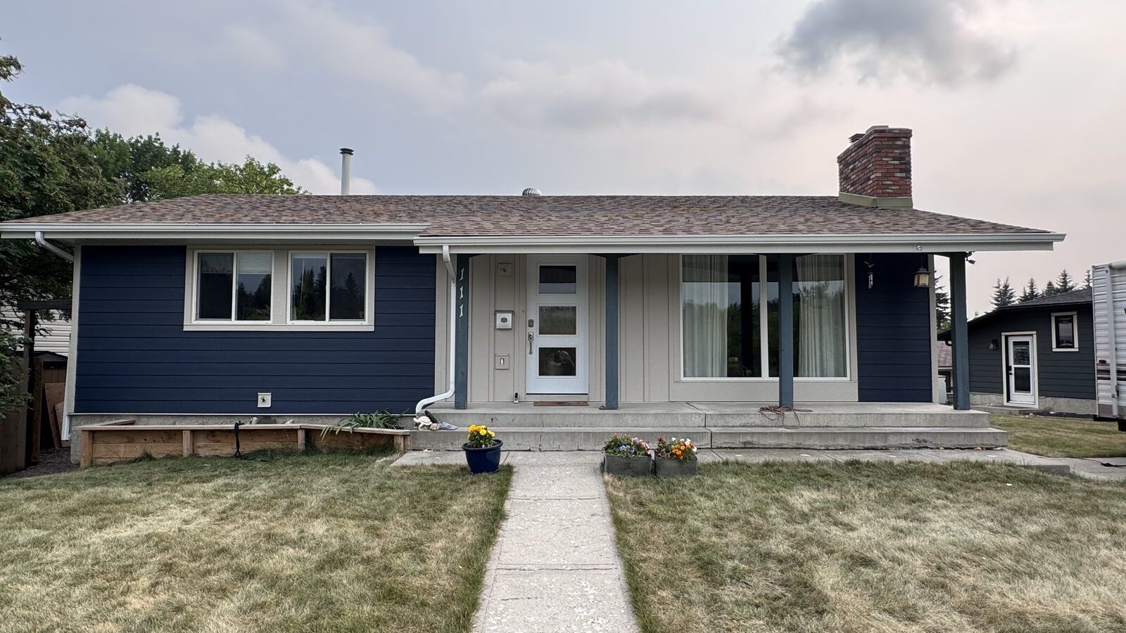 Navy fibre cement lap siding with hand-painted trim on a Calgary bungalow, front elevation