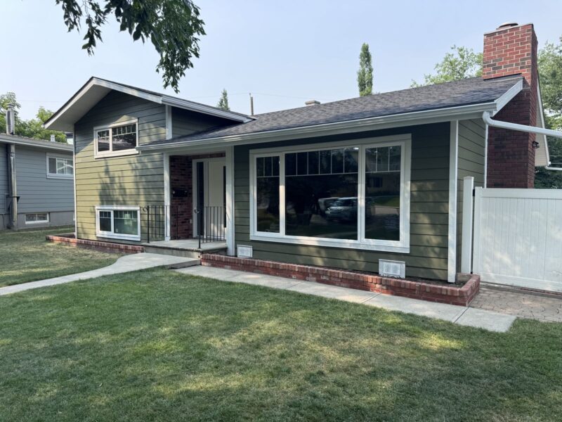 Sage green lap siding with white trim and a brick chimney