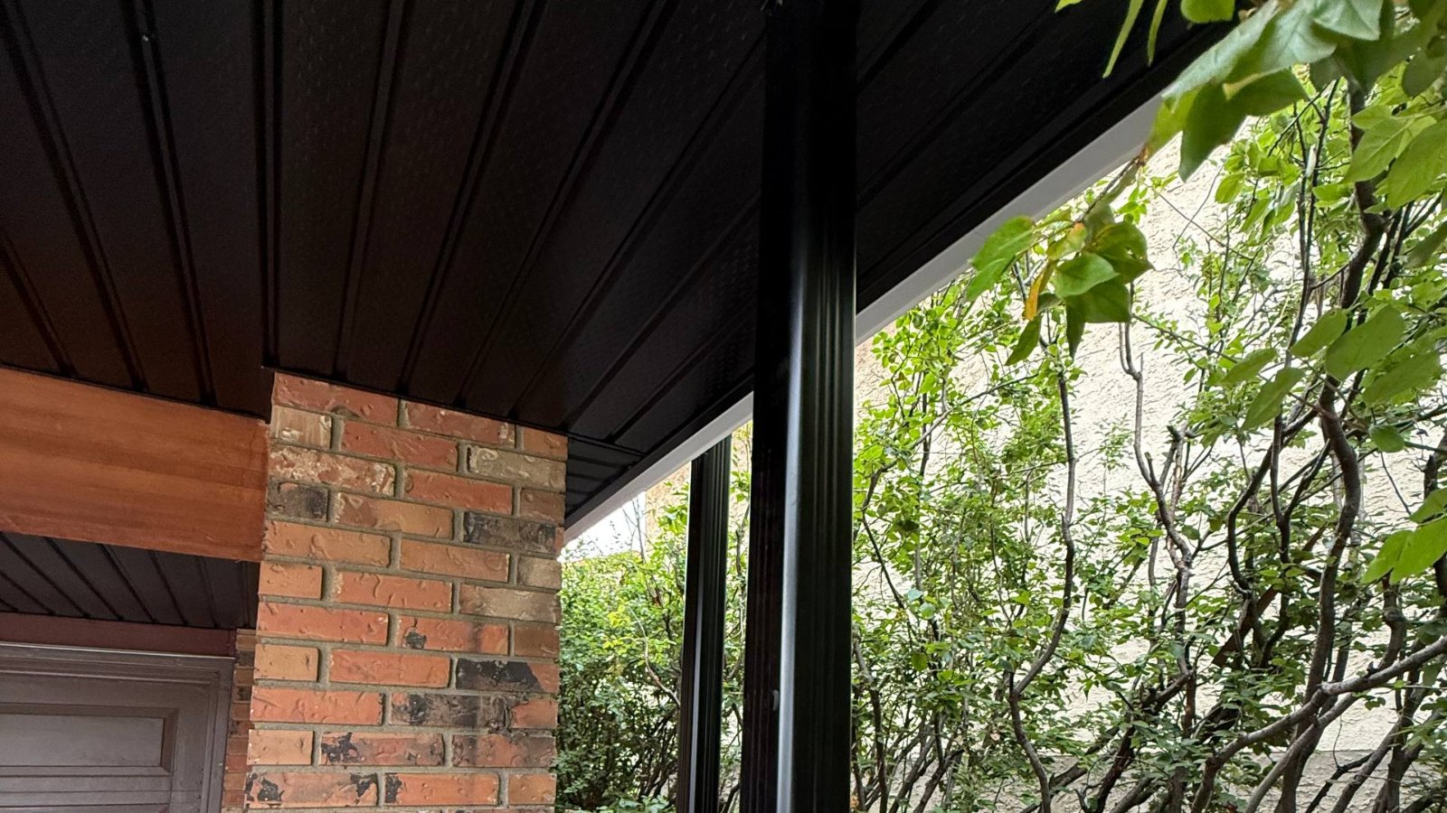 Dark vented soffit and fascia above a brick porch column on a Calgary home