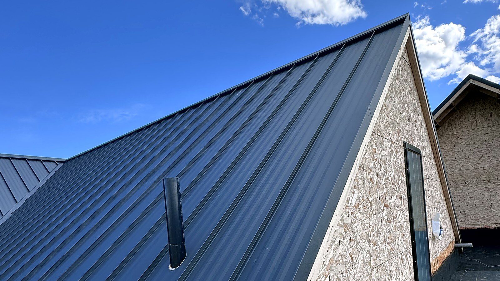 Standing seam panels running up a roof plane against a blue sky