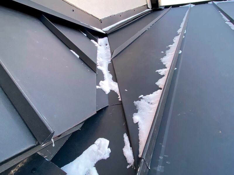 Close-up of snow sitting along a standing seam on a metal roof
