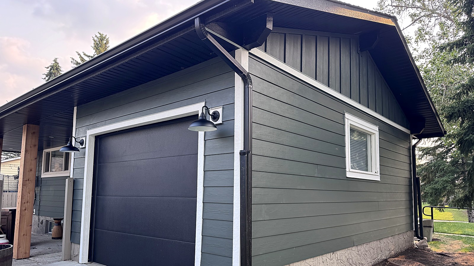 Green lap and board-and-batten siding on a detached garage after a Roof Bros siding job