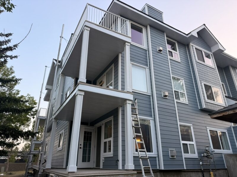 Blue fibre cement lap siding with white trim and columns on a three-storey home